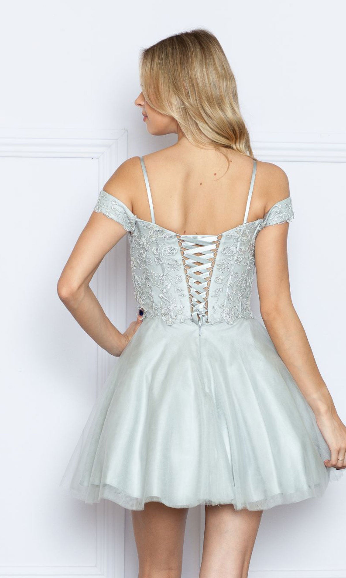 A woman faces away from the camera in the Lace-Up Off-Shoulder Short Babydoll Hoco Dress9234, a light blue homecoming dress with a lace-up back and tulle skirt.